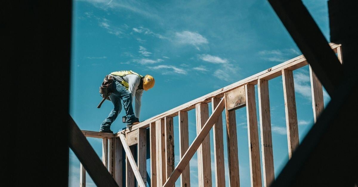 Worker framing a building with blue sky in background